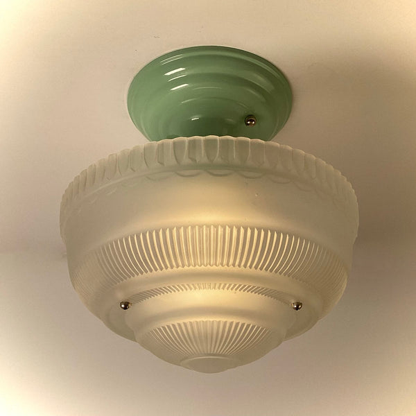 Vintage semi-flush ceiling light illuminated, featuring frosted ribbed glass shade and green metal canopy