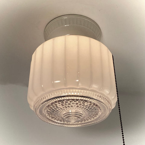 Bottom view of a vintage milk glass ceiling light fixture with a decorative clear glass prism base