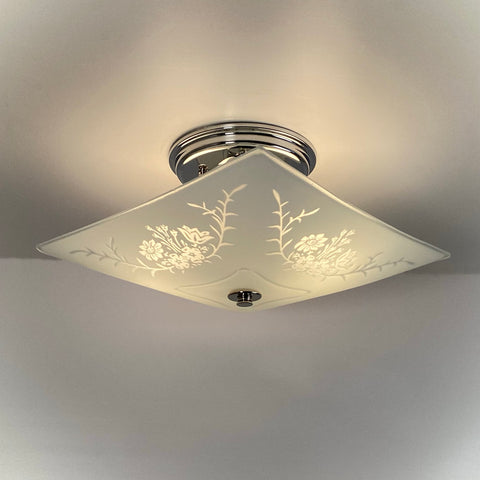 Vintage square frosted glass ceiling light illuminated, showing etched floral and botanical design