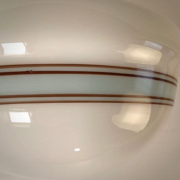 Macro view of horizontal decorative bands on an opal glass lamp shade, cool white lighting.