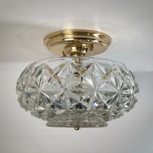 Mid-century crystal flush mount ceiling light with faceted diamond starburst glass shade and polished brass canopy, unlit and photographed against a white ceiling — Vintporium.