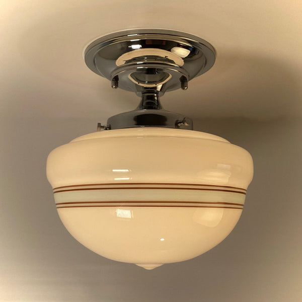 Polished chrome semi-flush mount schoolhouse light with brown and mint striped glass, warm illumination.