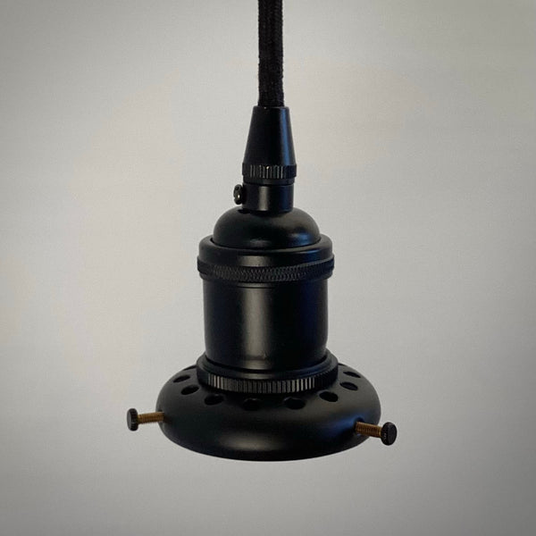 A side profile of a black industrial-style pendant light socket assembly hanging from a black cloth cord, showing the ventilated shade holder and adjustment screws.