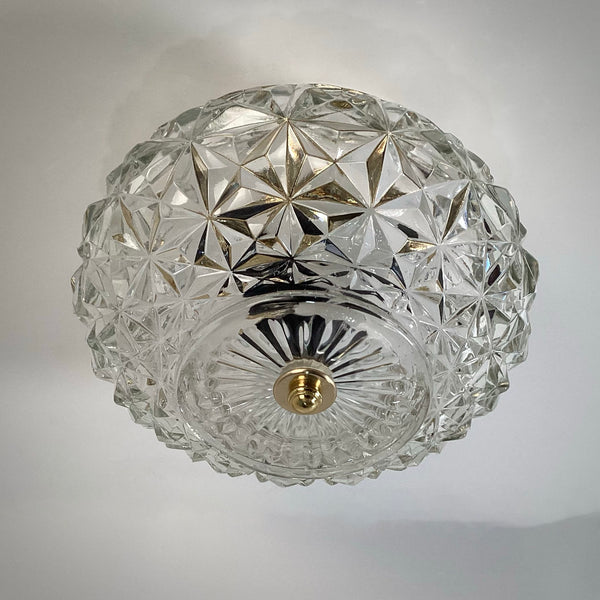 Bottom view of a mid-century crystal flush mount ceiling light featuring a clear diamond starburst glass pattern and polished brass finial, unlit against a white ceiling — Vintporium.