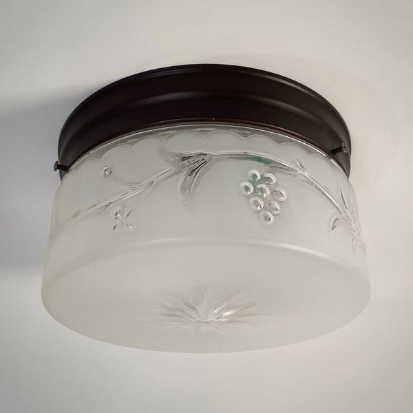 Post-war frosted glass ceiling fixture with embossed grapevine design and dark bronze mount, unlit view.