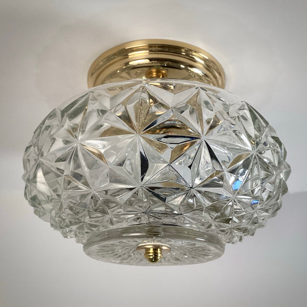 Vintage mid-century crystal flush mount ceiling light featuring a clear diamond starburst patterned glass shade and polished brass canopy, photographed against a white ceiling — Vintporium.
