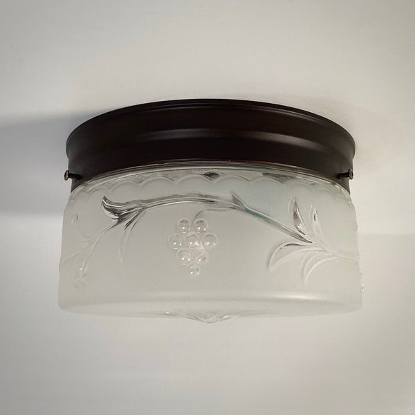 Vintage pressed-glass flush-mount ceiling light from the 1940s with clear grapevine motif and frosted starburst base.