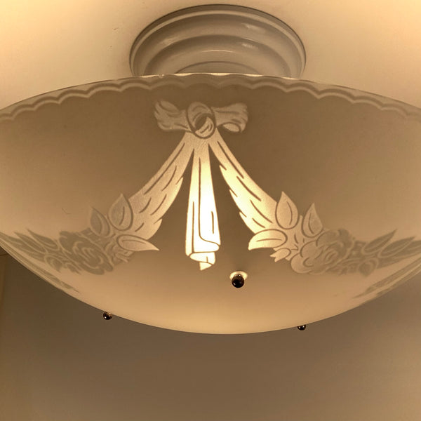 Close-up of enameled ribbon and floral motif on a 1950s semi-flush ceiling light