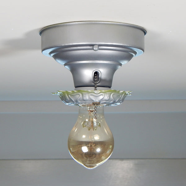 The restored flush mount fixture has a new glazed porcelain pull chain socket, wires, and a silver and green two-tone enamel paint finish. The fixture has been cleaned and detailed and has mounting hardware for convenient installation. Available at www.vintporium.com