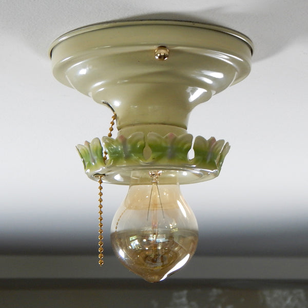 The antique flush mount ceiling light fixture features charming ivory, green and pink paint job and is topped with polished brass highlights. Even though the fixture has been clean and detailed it still retains much of its aging and wear. It also includes the hardware for easy installation. Available at www.vintporium.com