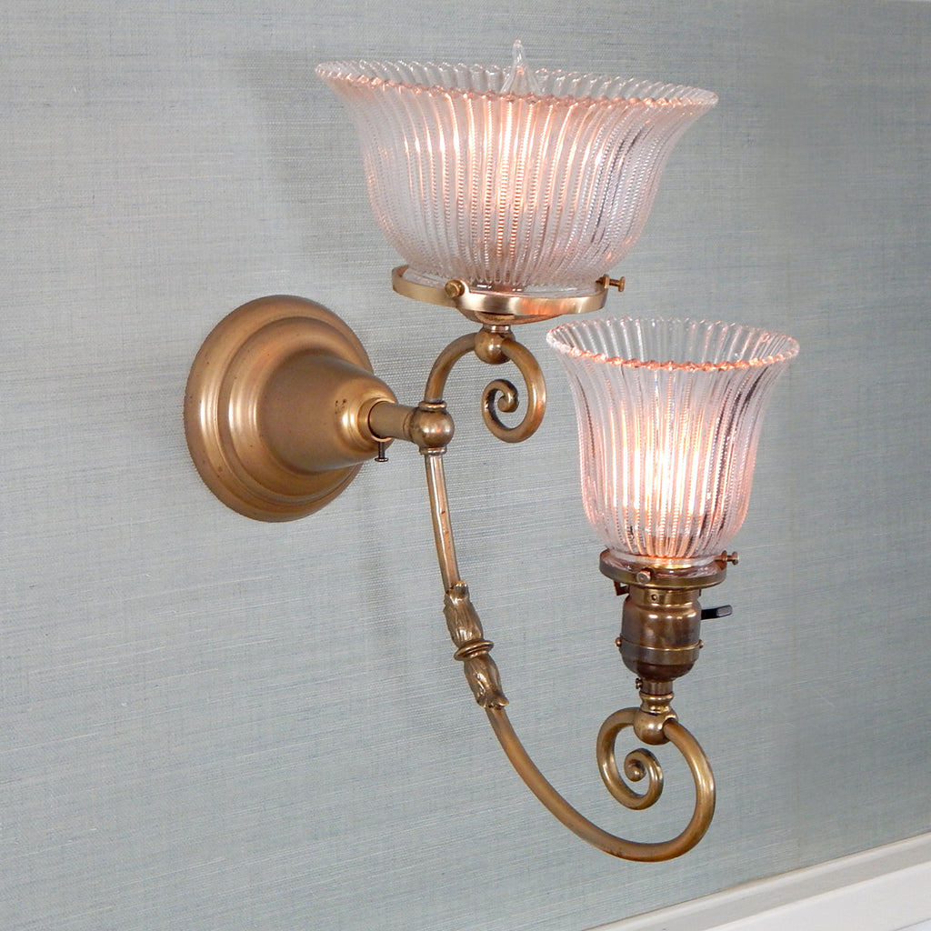 This renovated antique Victorian-era electric sconce has been rewired with numerous new parts added. Circa 1905ish, its naturally aged brass finish emphasizes its age and unique character. The fixture features new wiring, sockets, etc., and has been cleaned, yet not overly detailed. The sconce comes with mounting hardware making it convenient to install. Available at www.vintporium.com
