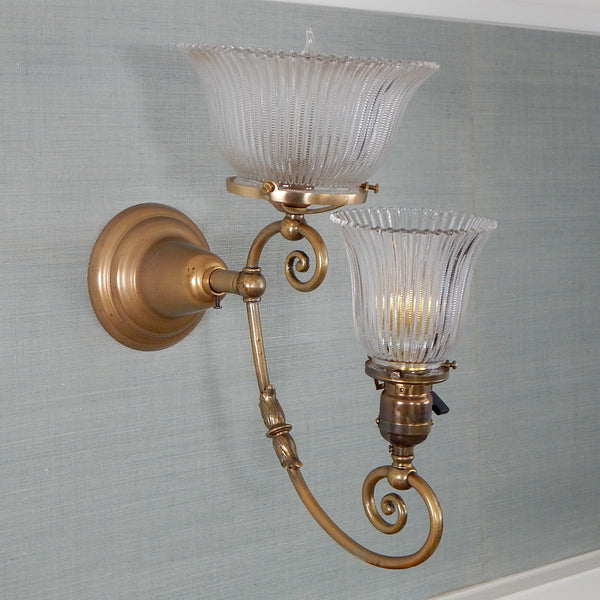 This renovated antique Victorian-era electric sconce has been rewired with numerous new parts added. Circa 1905ish, its naturally aged brass finish emphasizes its age and unique character. The fixture features new wiring, sockets, etc., and has been cleaned, yet not overly detailed. The sconce comes with mounting hardware making it convenient to install. Available at www.vintporium.com