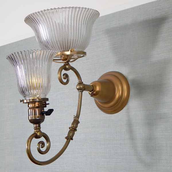 This renovated antique Victorian-era electric sconce has been rewired with numerous new parts added. Circa 1905ish, its naturally aged brass finish emphasizes its age and unique character. The fixture features new wiring, sockets, etc., and has been cleaned, yet not overly detailed. The sconce comes with mounting hardware making it convenient to install. Available at www.vintporium.com