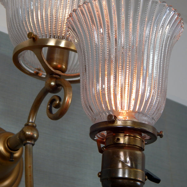 This renovated antique Victorian-era electric sconce has been rewired with numerous new parts added. Circa 1905ish, its naturally aged brass finish emphasizes its age and unique character. The fixture features new wiring, sockets, etc., and has been cleaned, yet not overly detailed. The sconce comes with mounting hardware making it convenient to install. Available at www.vintporium.com